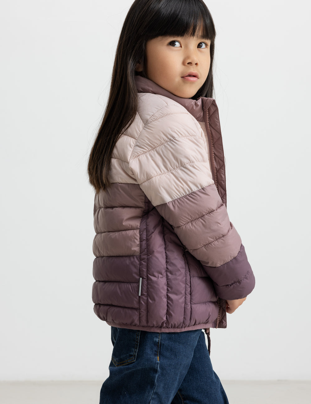 Pige i vatteret jakke med striber i rosa og lilla toner