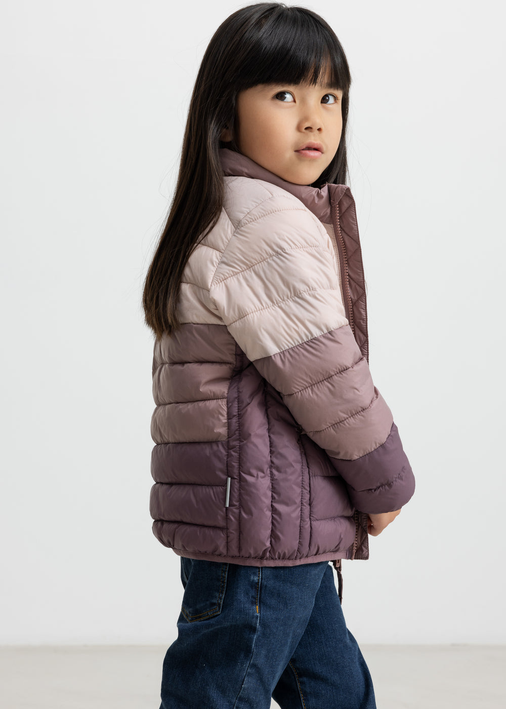 Pige i vatteret jakke med striber i rosa og lilla toner