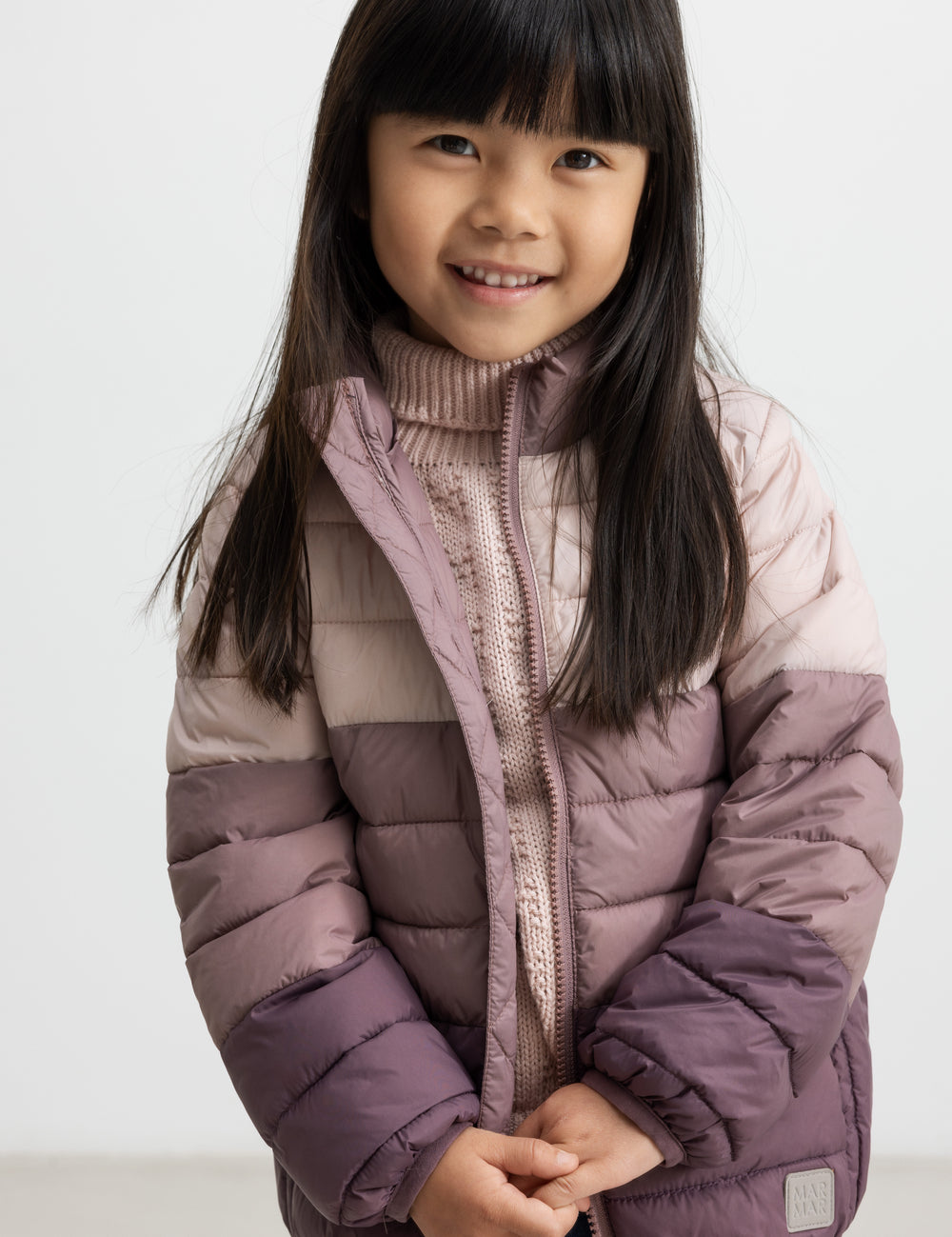 Pige iført vatteret jakke i rosa og lilla nuancer