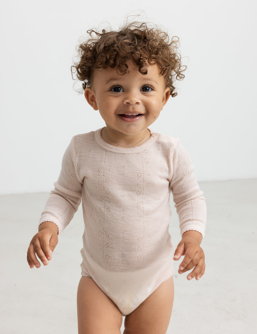 Baby iført lyserød body i merinould