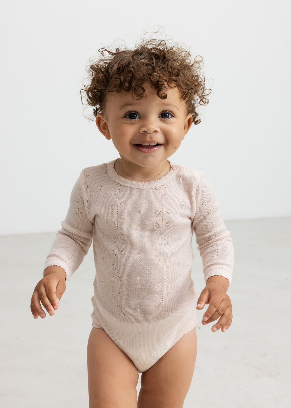 Baby iført lyserød body i merinould