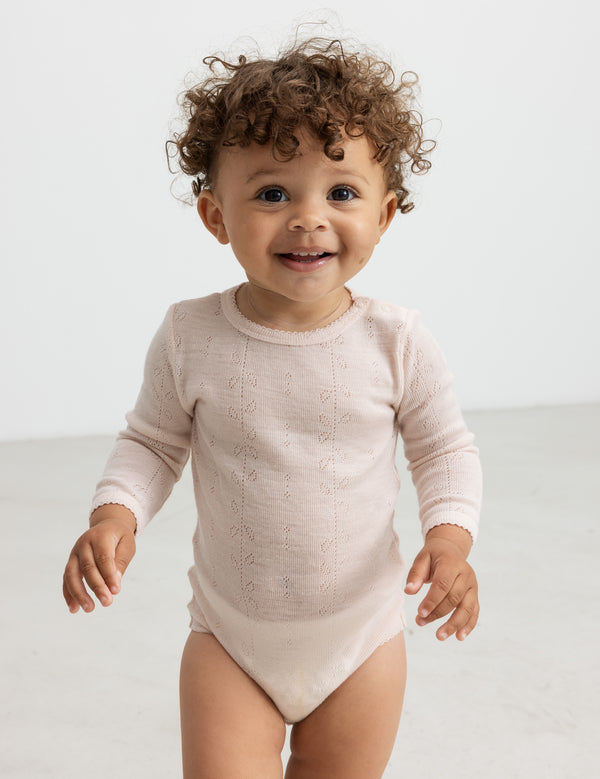 Baby i lyserød pointelle-body med lange ærmer