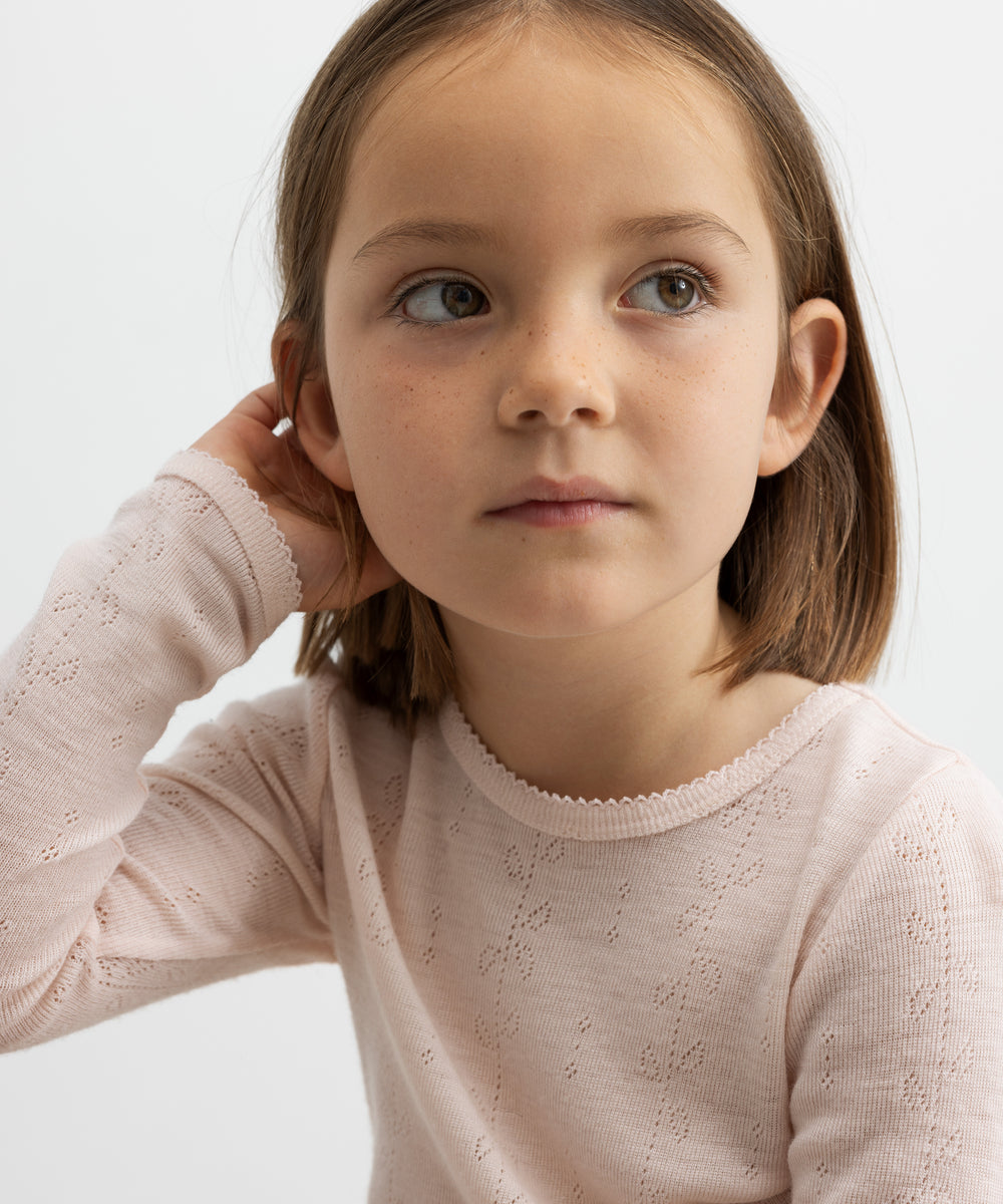 Pige iført lyserød bluse i merinould