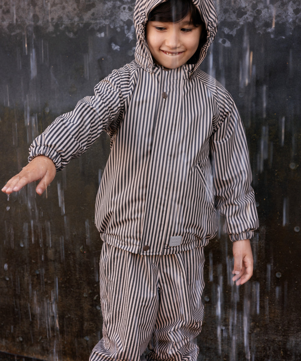 Barn iført brunt stribet regnsæt med hætte