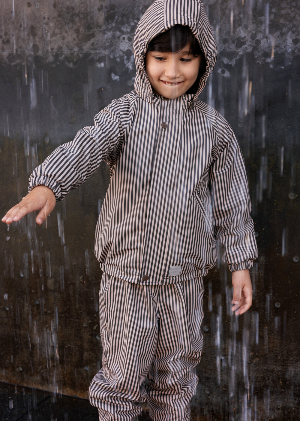 Barn iført brunt stribet regnsæt med hætte