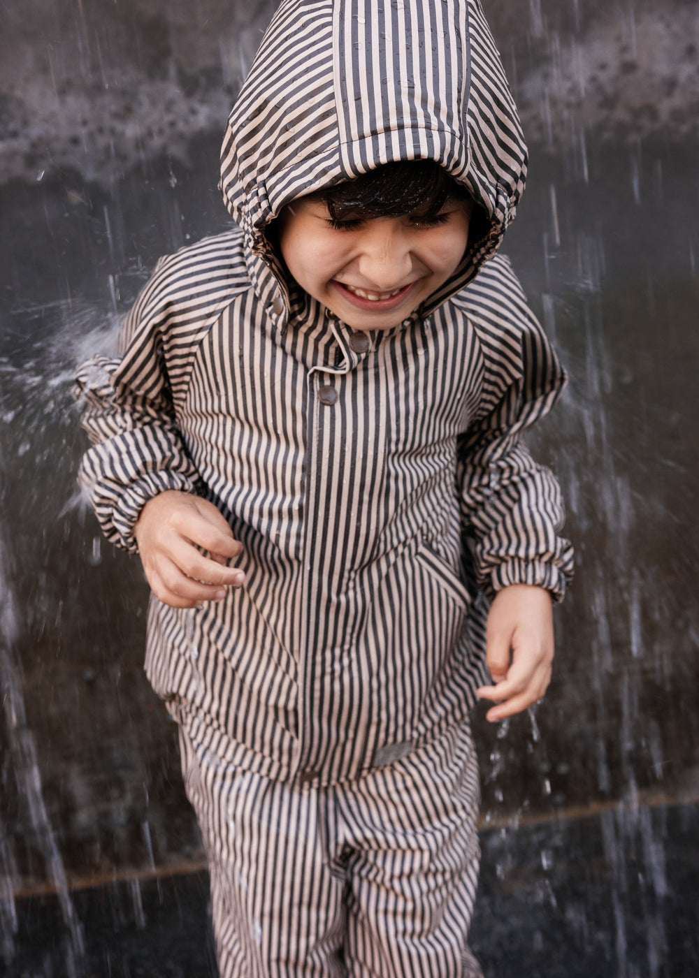 Barn iført stribet regnsæt med hætte