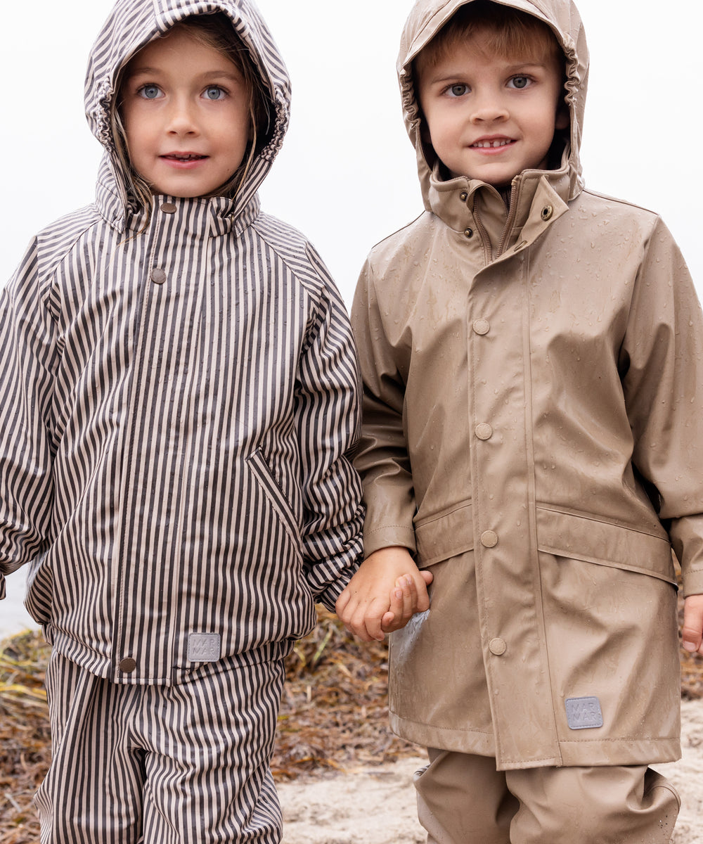 To børn iført regntøj, det ene barn bærer beige regnbukser og jakke