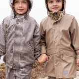 To børn iført regntøj, det ene barn bærer beige regnbukser og jakke