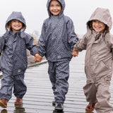 Tre børn i regntøj, midterste barn iført mørkeblåt sæt med print og hætte