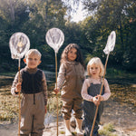 Tre børn i naturen iført regntøj, to med prikmønster og fiskenet
