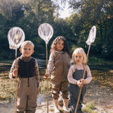 Tre børn i naturen iført regntøj, to med prikmønster og fiskenet