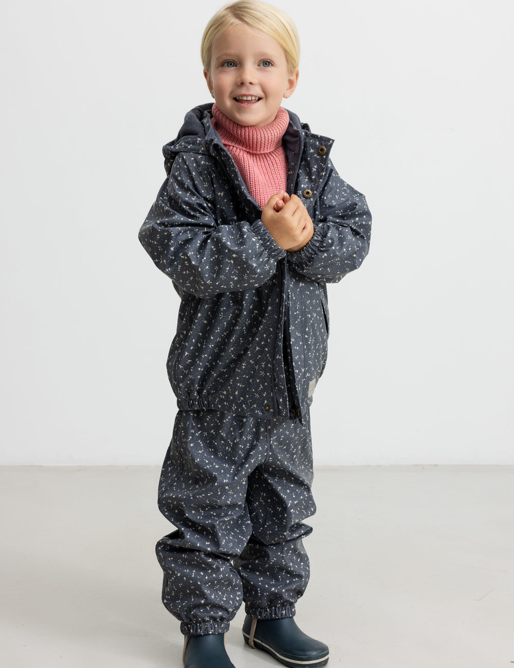 Børn iført mørkegråt regnsæt med prikker og lyserød trøje