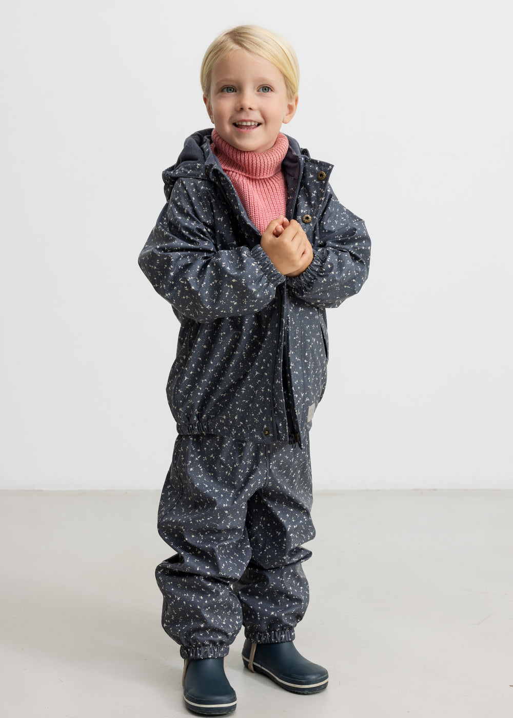 Børn iført mørkegråt regnsæt med prikker og lyserød trøje