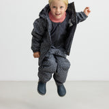 Børn hopper iført mørkegråt regnsæt med prikker og lyserød trøje