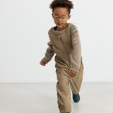 Børn løber indendørs iført beige selebukser