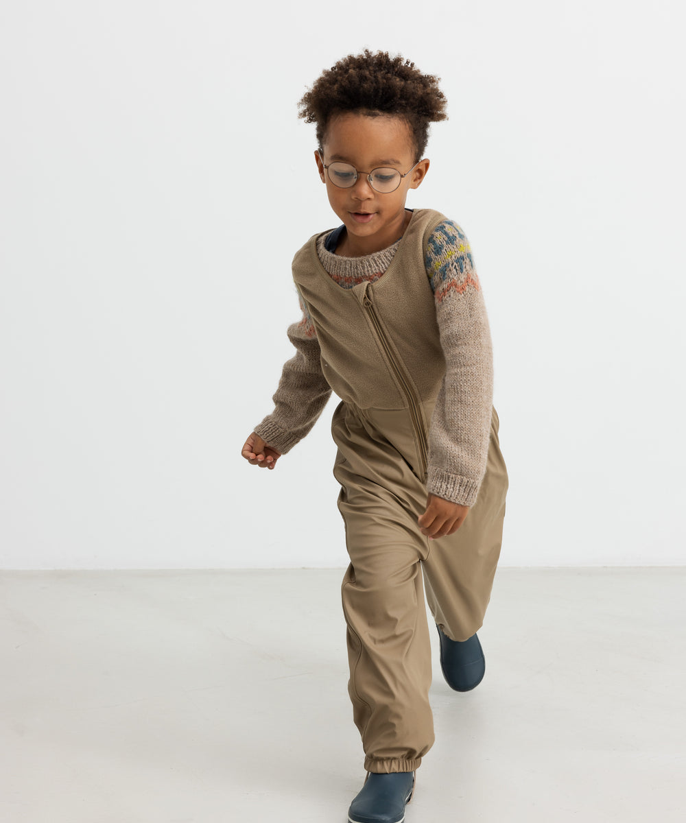 Dreng iført beige uldstrikbluse med mønster leger