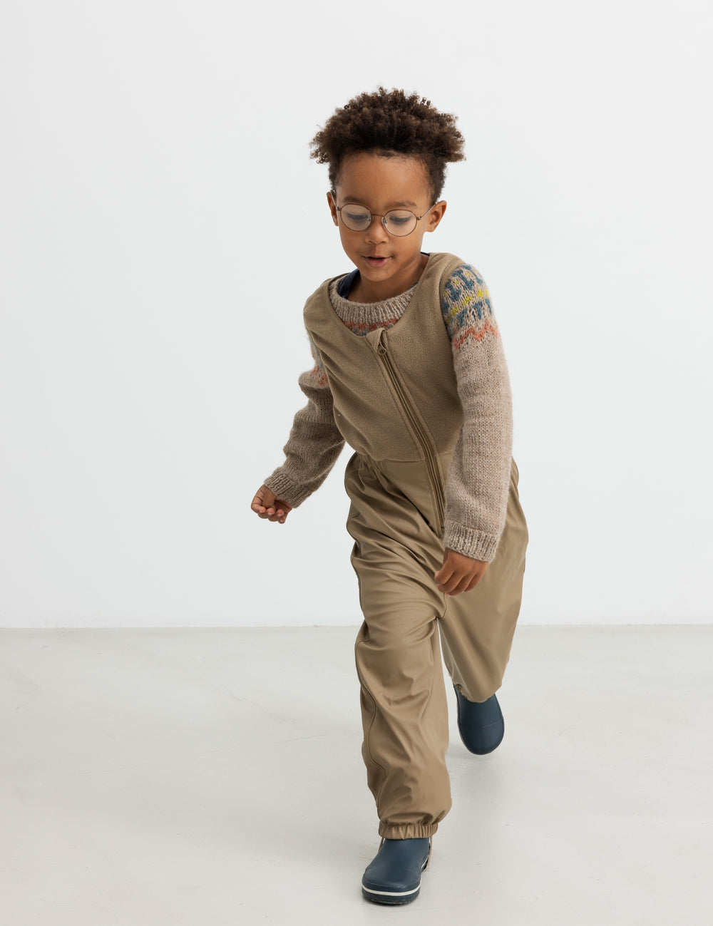 Gutten iført beige uldstrikbluse med mønster leger