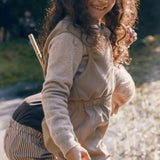 Pige iført beige selebukser og lys trøje i naturen