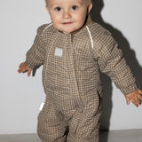 Baby iført brunternet termodragt, smilende og i bevægelse