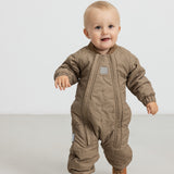 Baby iført brunternet termodragt, går mod kameraet