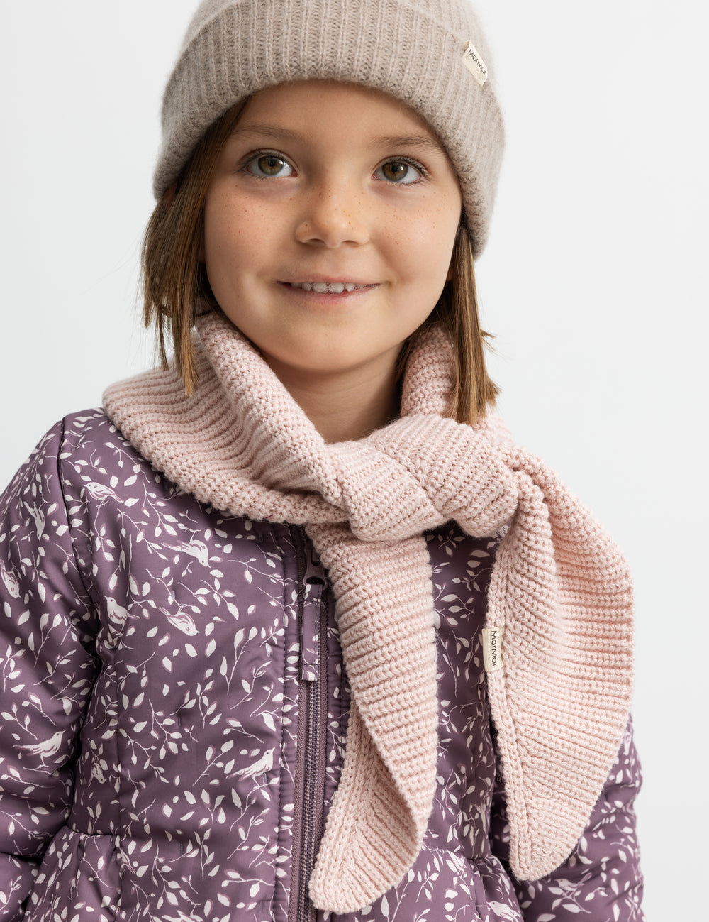 Barn iført lyserødt halstørklæde og en hue.