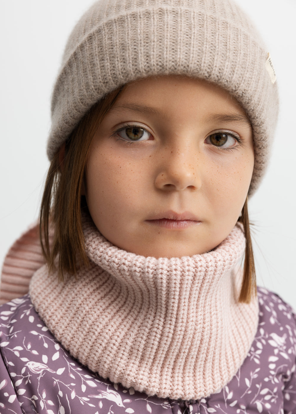 Barn iført lyserødt halstørklæde og hue