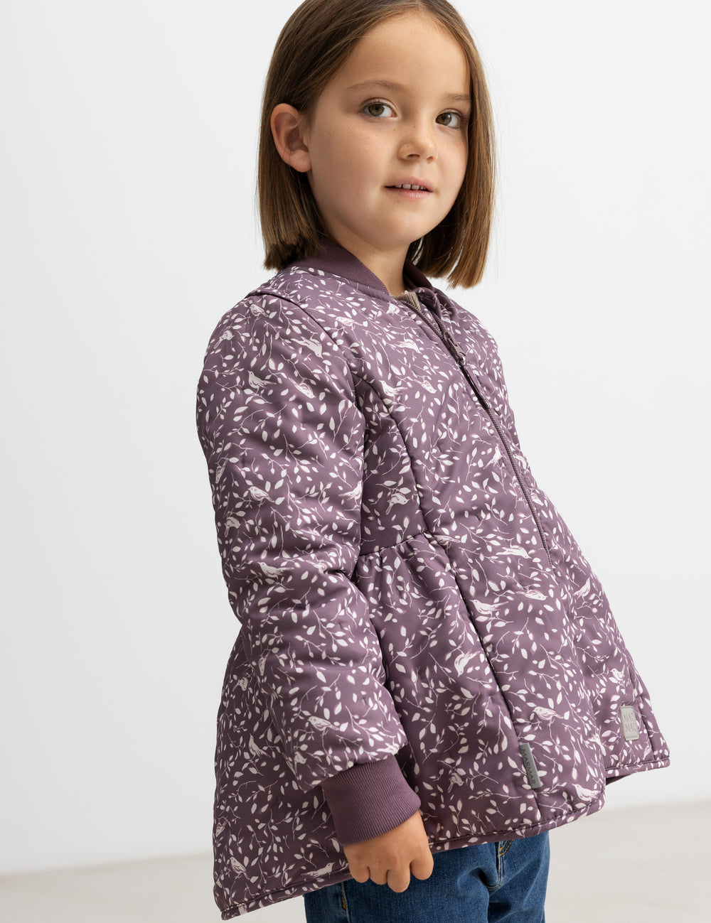 Barn iført støvlilla termojakke med print, set fra siden