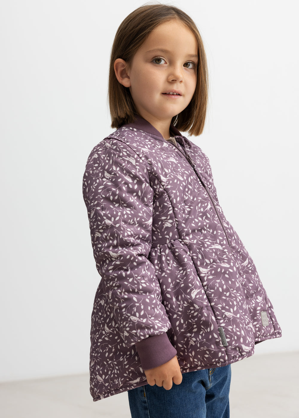 Barn iført støvlilla termojakke med print, set fra siden