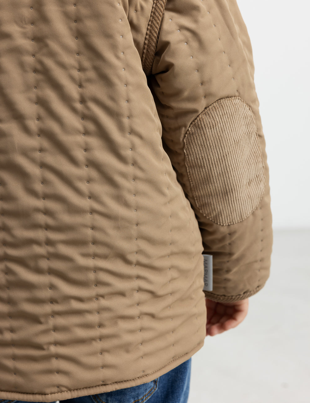 Nærbillede af lomme og quiltet struktur på brun termojakke
