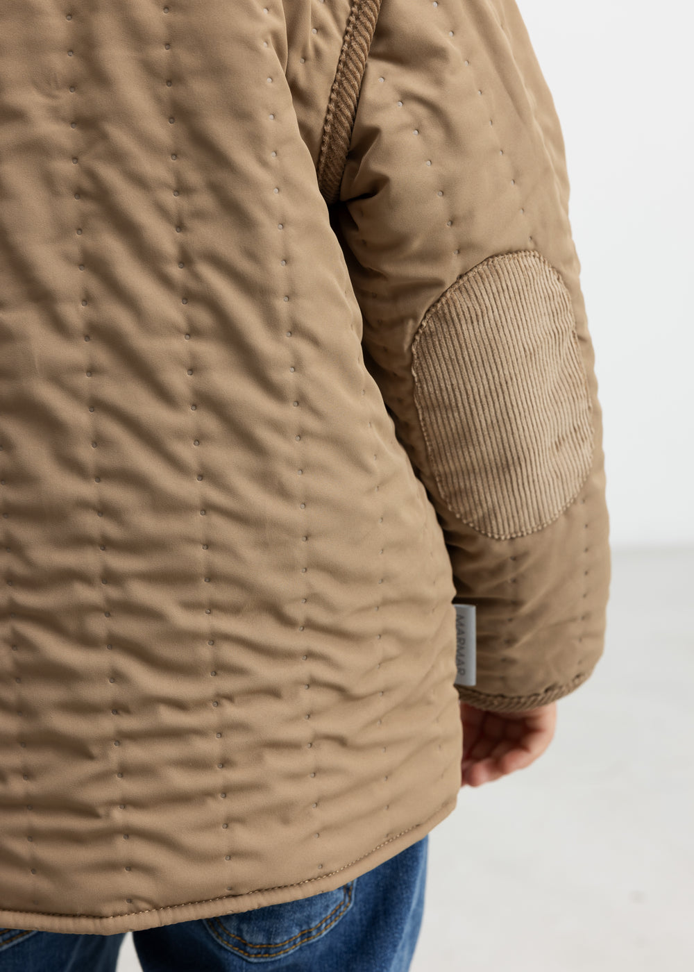 Nærbillede af lomme og quiltet struktur på brun termojakke