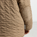 Nærbillede af lomme og quiltet struktur på brun termojakke
