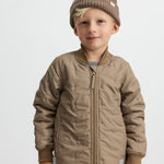 Barn iført brunternet termojakke og matchende bukser, smilende