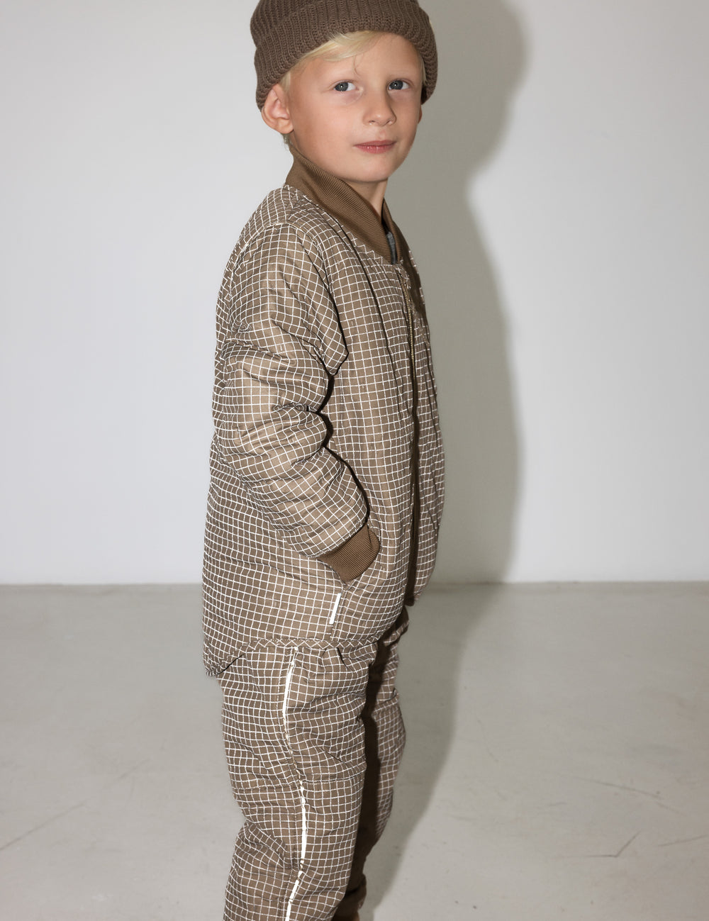 Barn i brunternet termotøj med hætte, hænderne i lommerne