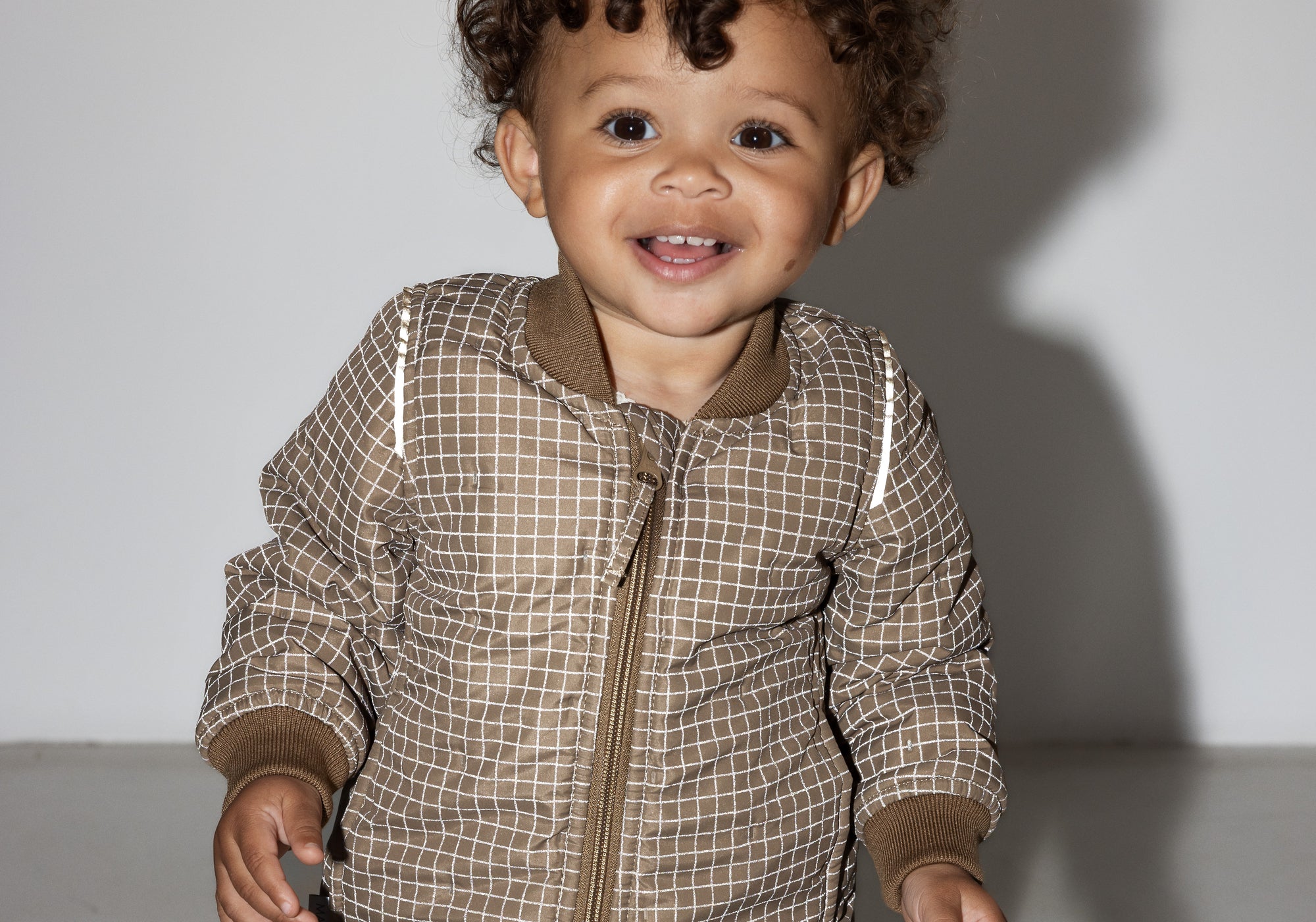 Smilende baby iført brunternet termodragt