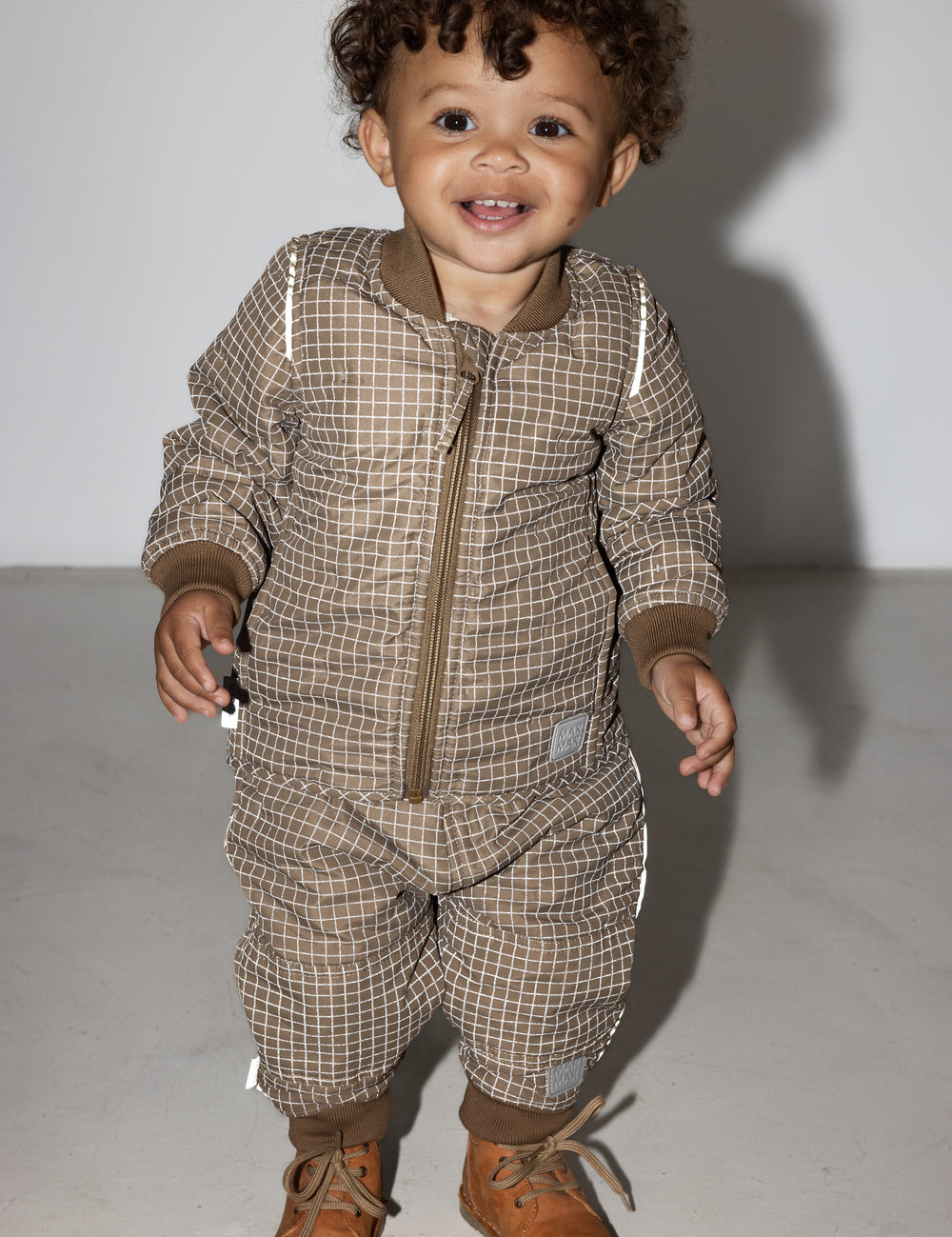 Lille barn i brunternet termotøj, smilende og i bevægelse