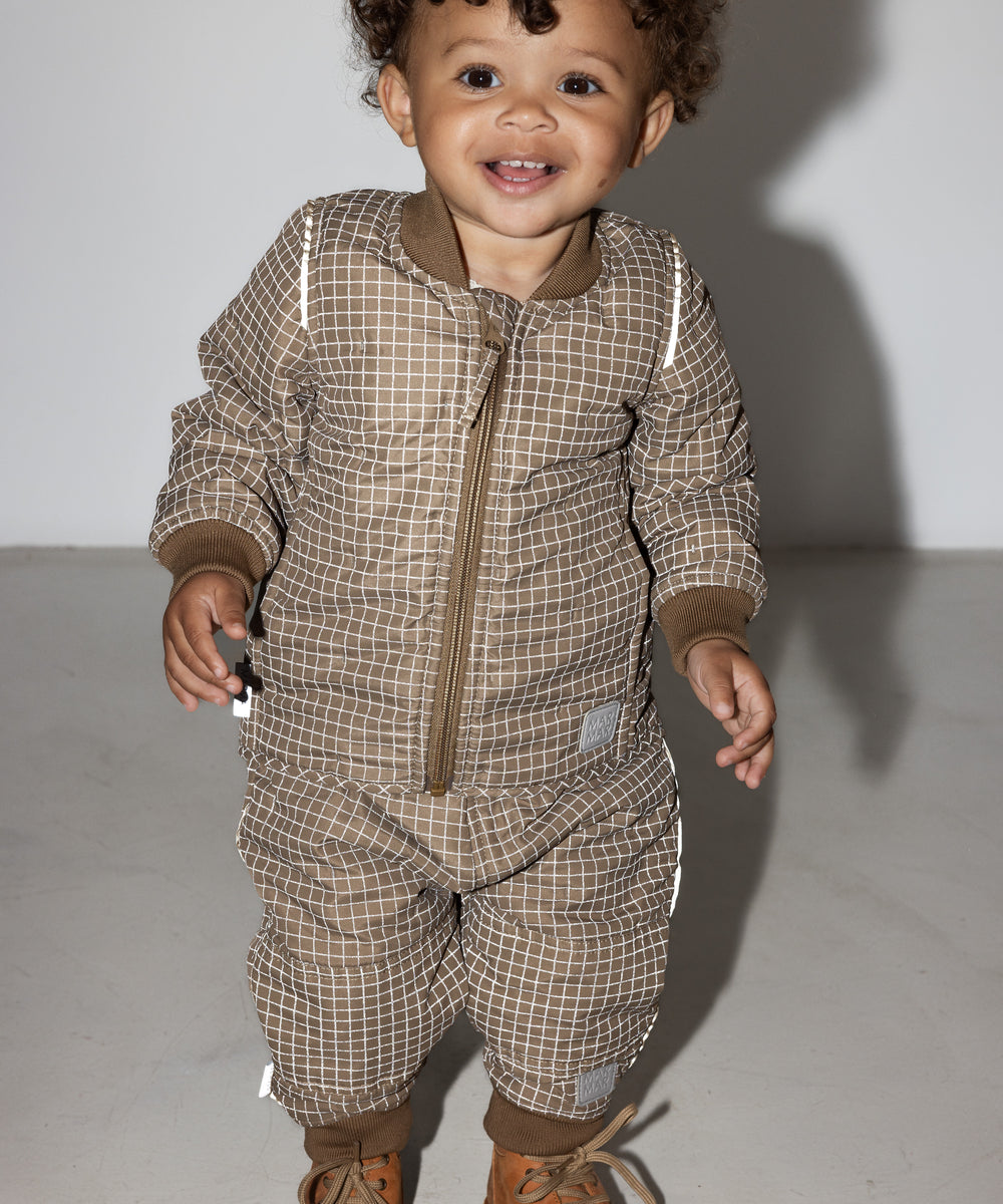 Lille barn i brunternet termotøj, smilende og i bevægelse