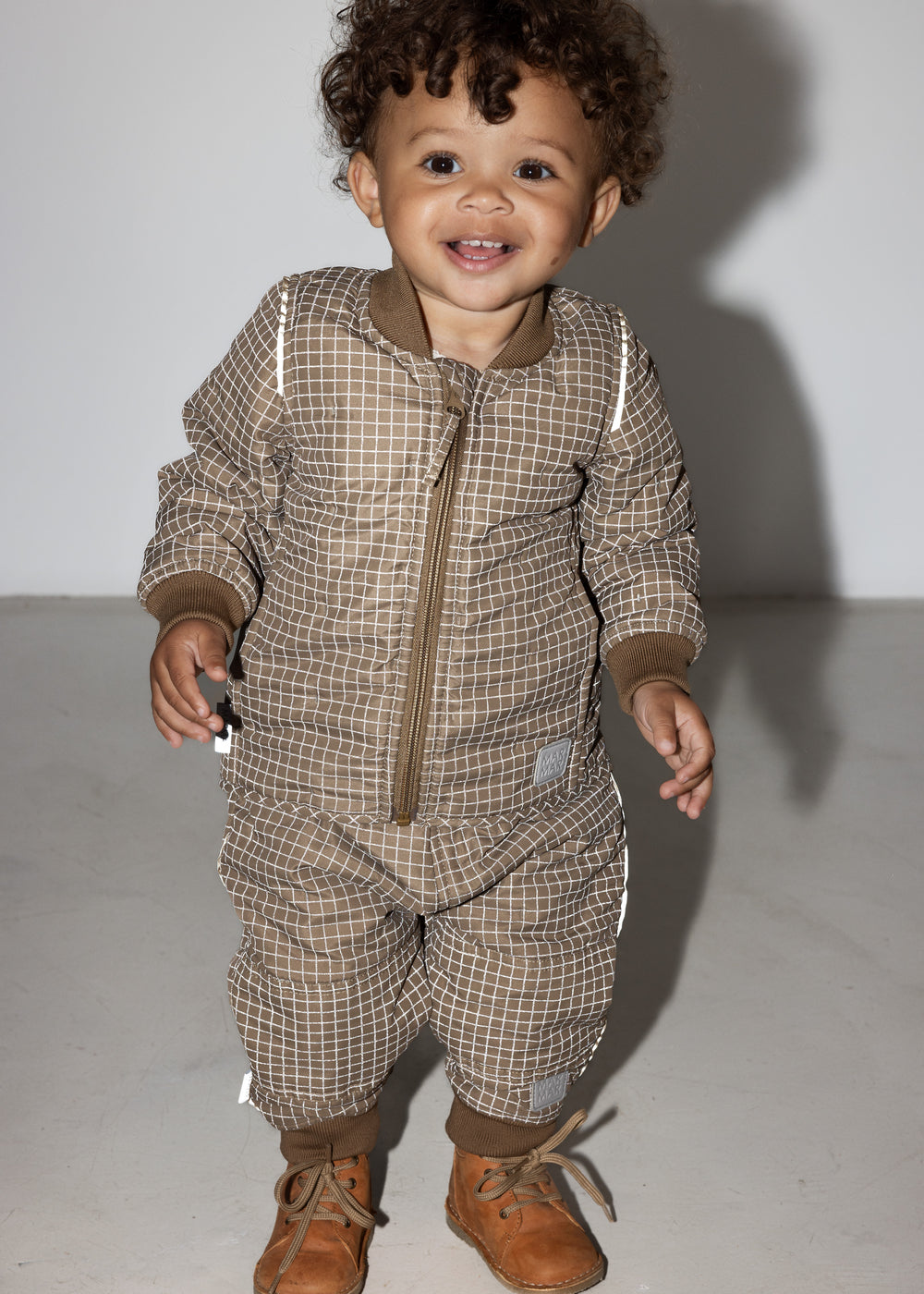 Lille barn i brunternet termotøj, smilende og i bevægelse