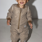 Lille barn i brunternet termotøj, smilende og i bevægelse