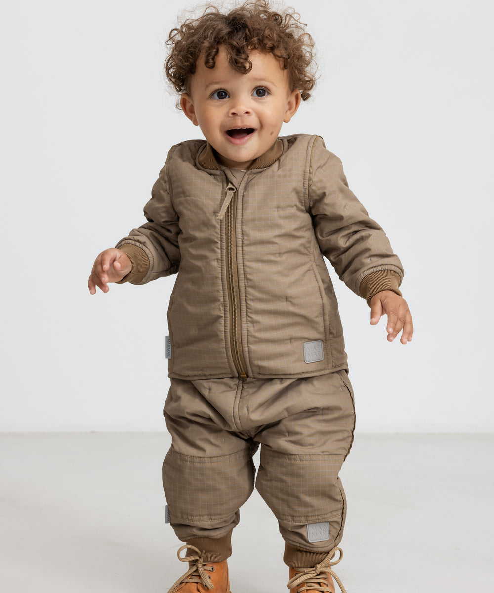 Lille barn i brunternet termotøj, smilende og i bevægelse