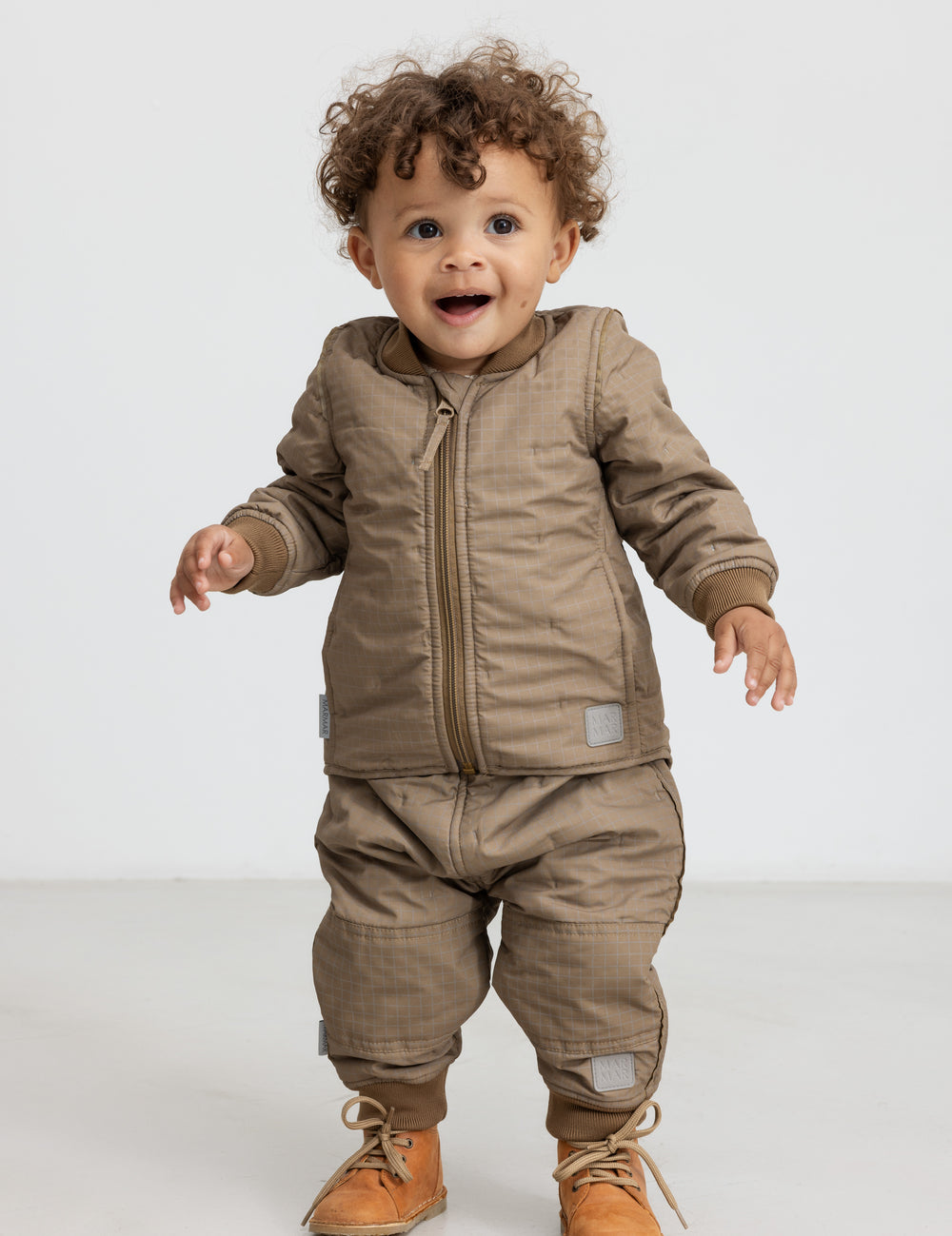 Lille barn i brunternet termotøj, smilende og i bevægelse