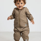 Lille barn i brunternet termotøj, smilende og i bevægelse