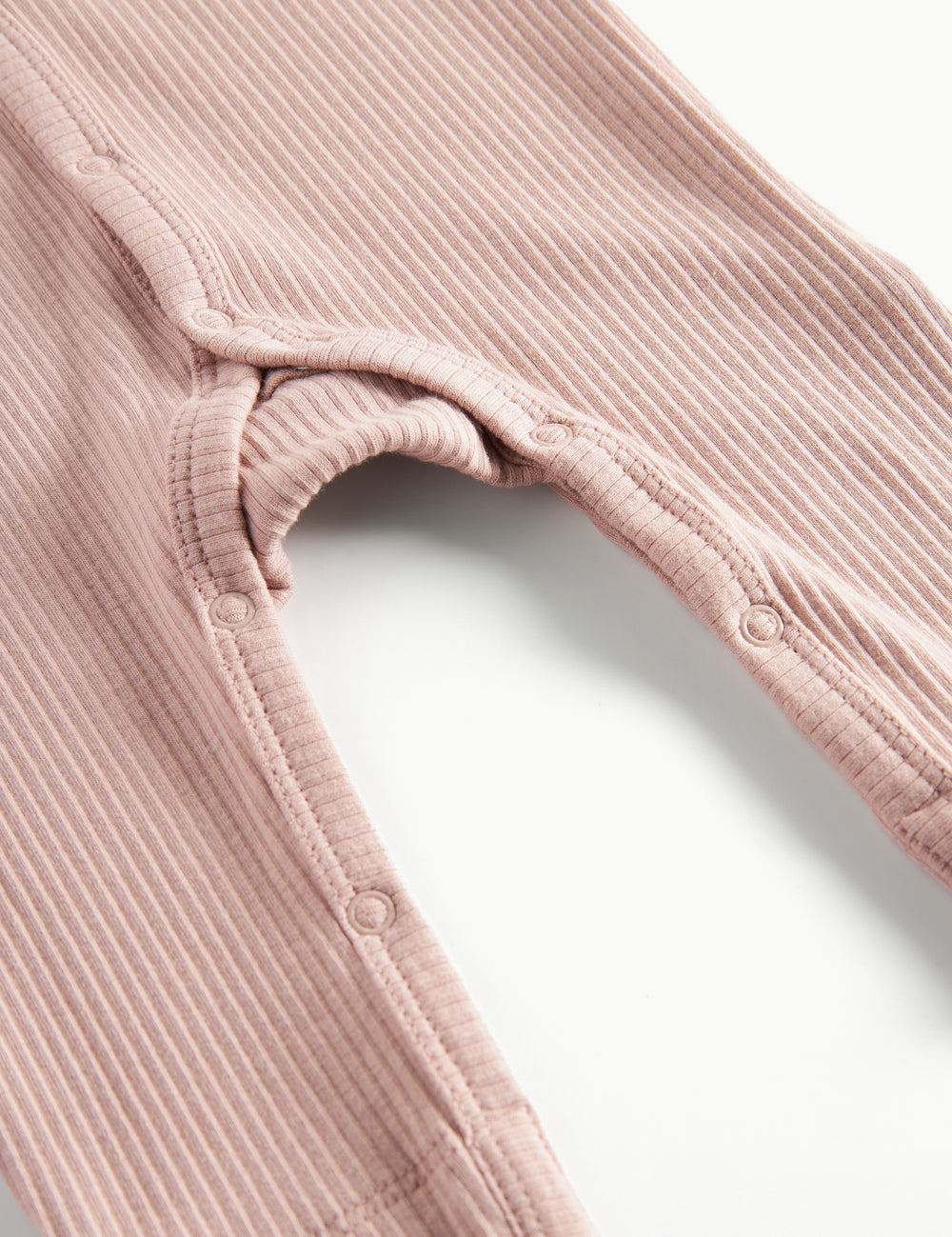 Ribbstrikket lyserød heldragt til baby i blødt materiale med lange ærmer og lange ben og tryknapper