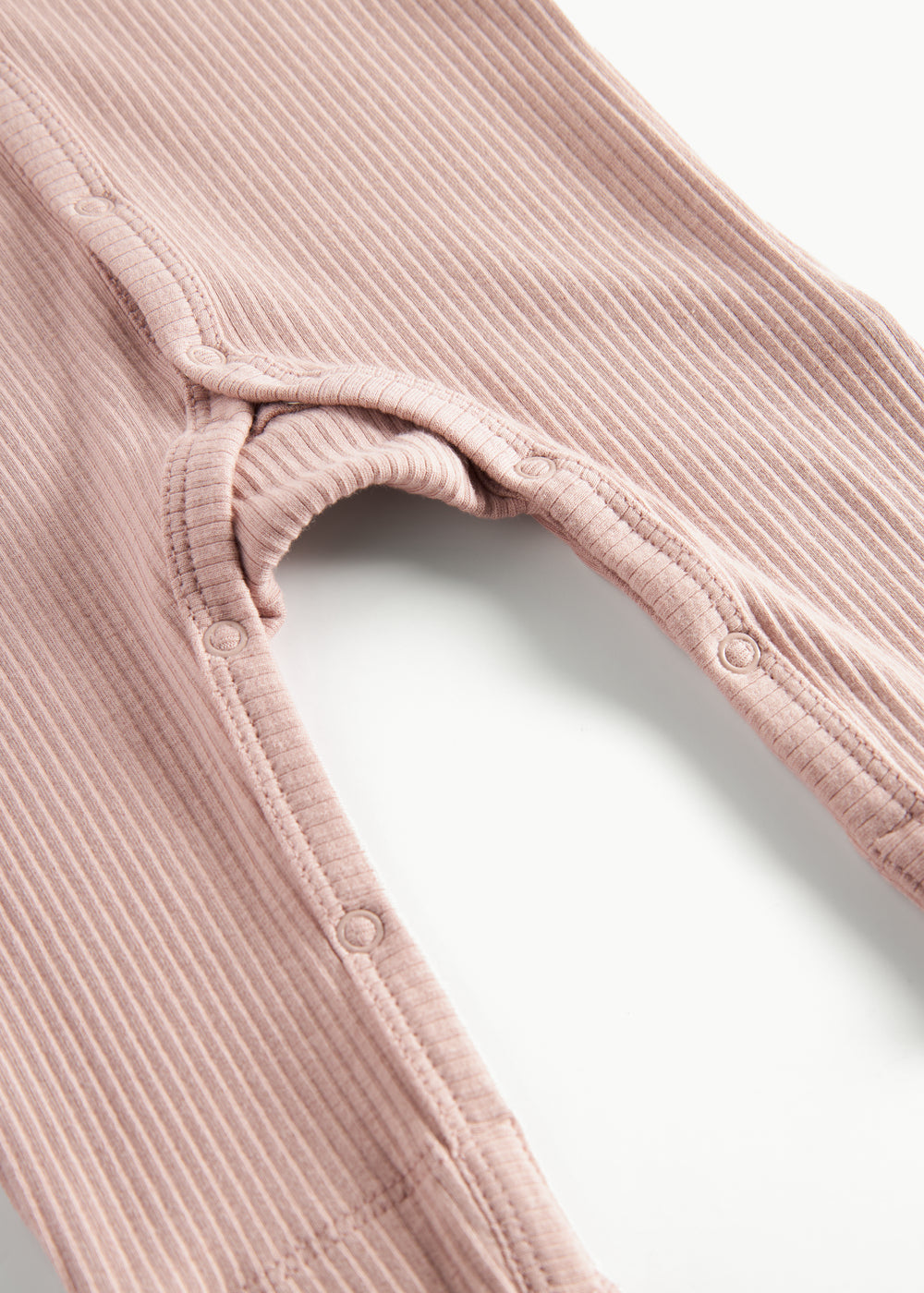 Ribbstrikket lyserød heldragt til baby i blødt materiale med lange ærmer og lange ben og tryknapper