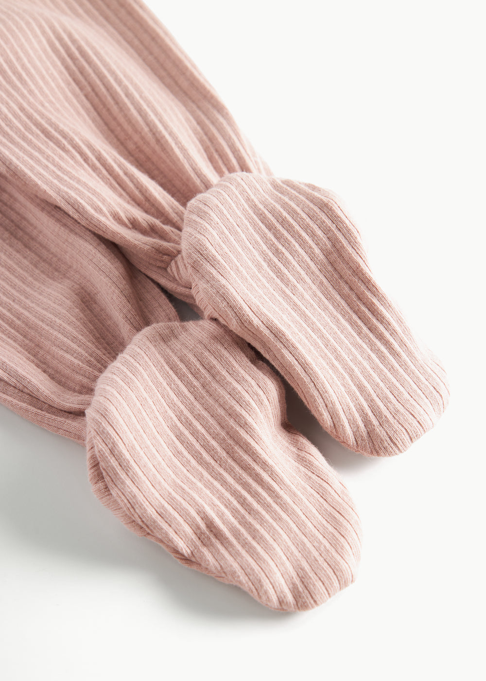 Detaljebillede af fod på lyserøde ribstrikkede bukser til baby