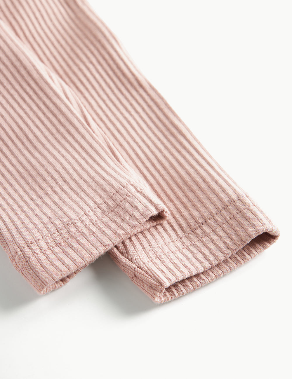 Detaljebillede af benåbning på lyserøde ribstrikkede bukser til børn