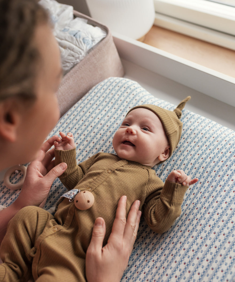 Baby i ribbstrikket brun heldragt til baby i blødt materiale med lange ærmer, lange ben, tryknapper og futter og brun babyhue