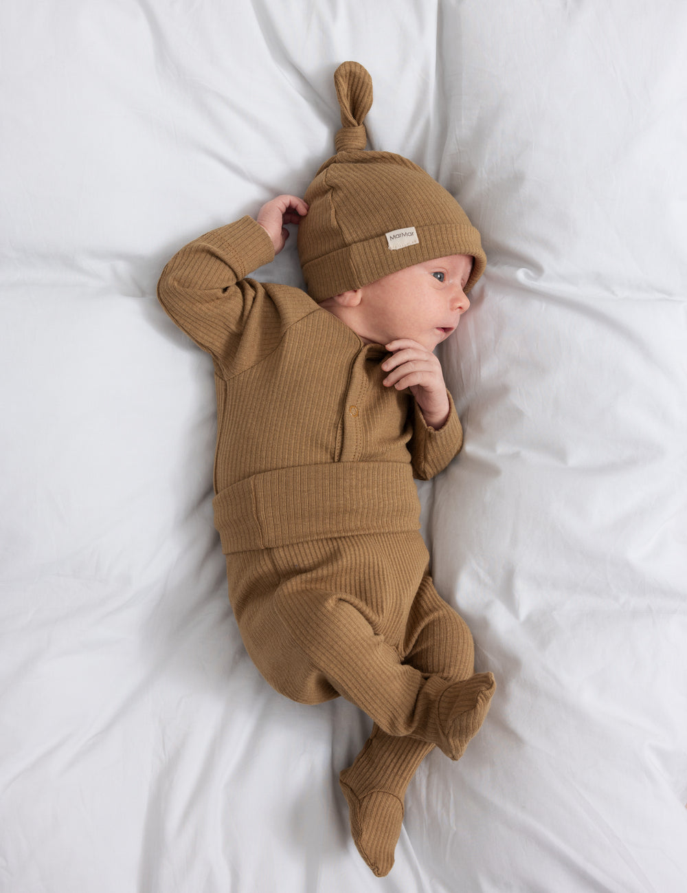 Baby med brun ribstrikket body med knapper foran og babyhue