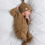 Baby iført brun ribstrikket babybody med knapper foran og babyhue