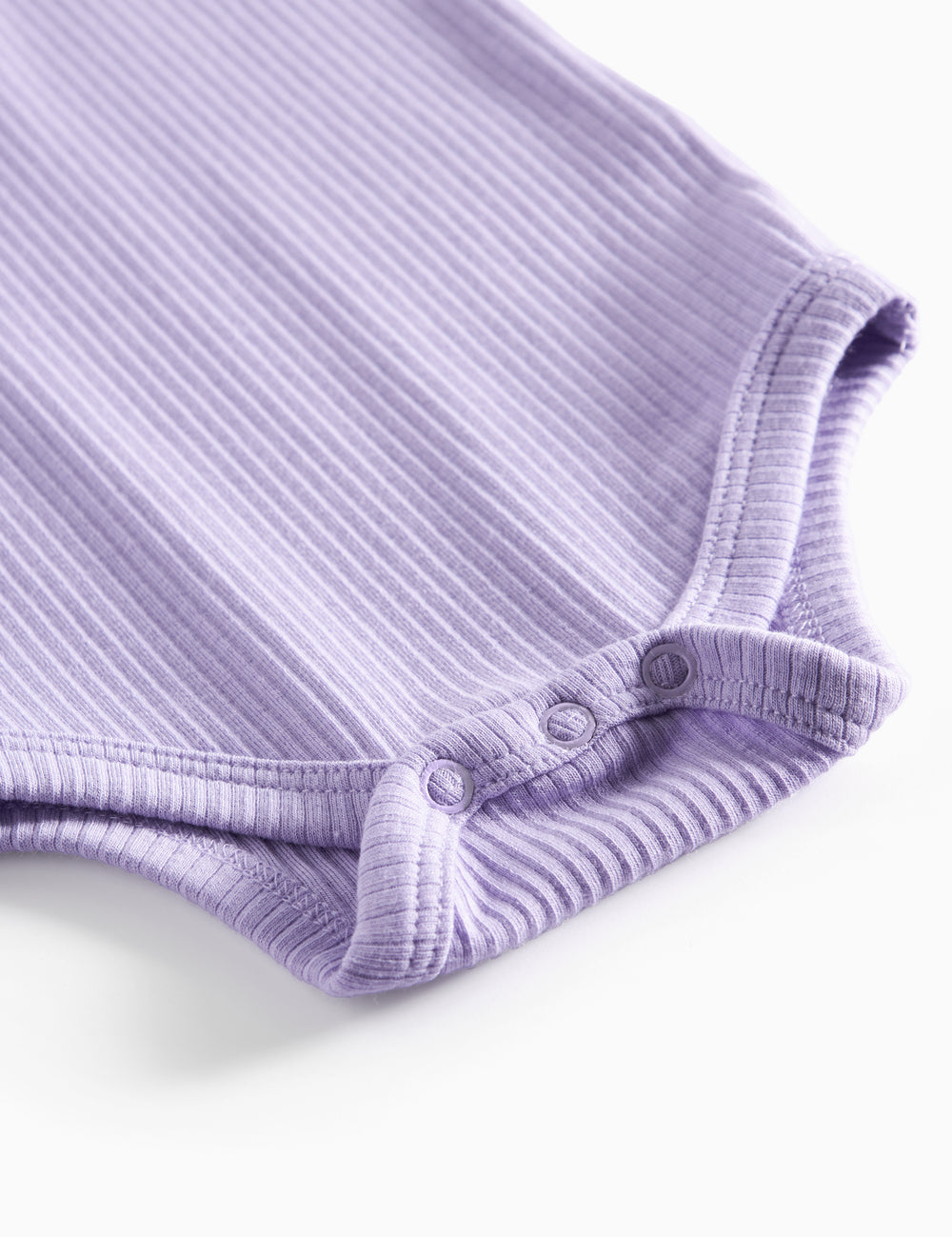 Lilla ribstrikket babybody med lange ærmer, stolpe knaplukning og trykknapper mellem benene