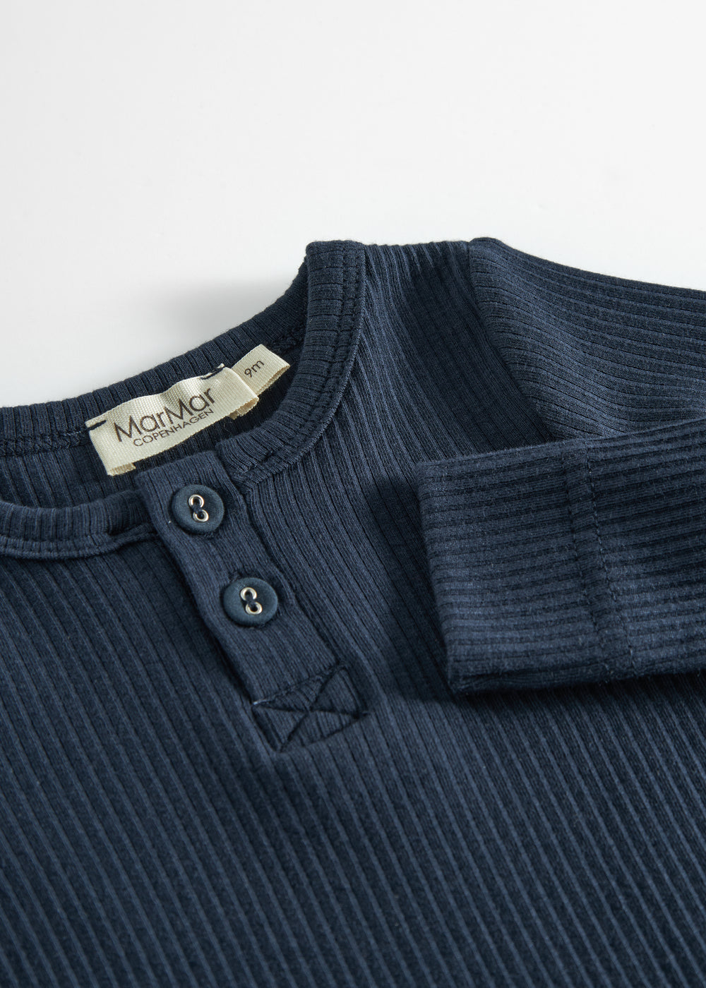 Blå ribstrikket babybody med lange ærmer, stolpe knaplukning og trykknapper mellem benene